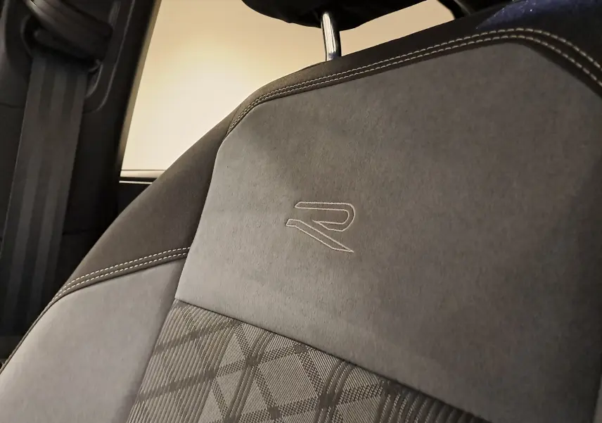 Gros plan sur le siège avant en tissu et alcantara gris avec logo R brodé, intérieur du Volkswagen Taigo noir intense.