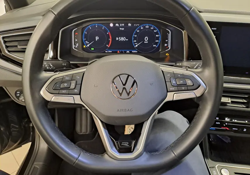 Vue intérieure centrée sur le volant cuir noir du Volkswagen Taigo 2025 avec tableau de bord numérique et commandes intégrées.