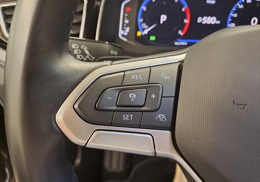 Gros plan sur les commandes au volant côté gauche du Volkswagen Taigo 2025, avec affichage digital en arrière-plan.
