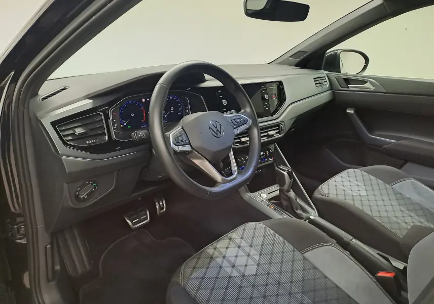 Vue intérieure côté conducteur du Volkswagen Taigo 2025 noir intense, volant multifonction et sièges tissu à motif géométrique.
