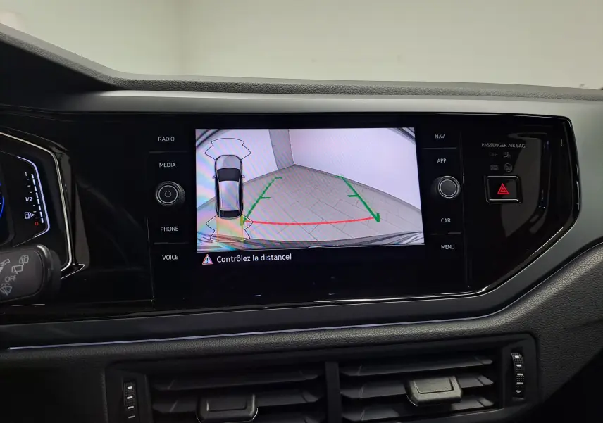Vue intérieure du tableau de bord du Volkswagen Taigo 2025, écran central affichant la caméra de recul avec alertes de distance.