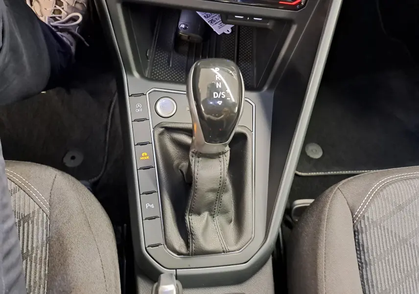 Vue plongeante sur la console centrale du Volkswagen Taigo 2025, avec levier de boîte auto noir et sièges tissu gris.