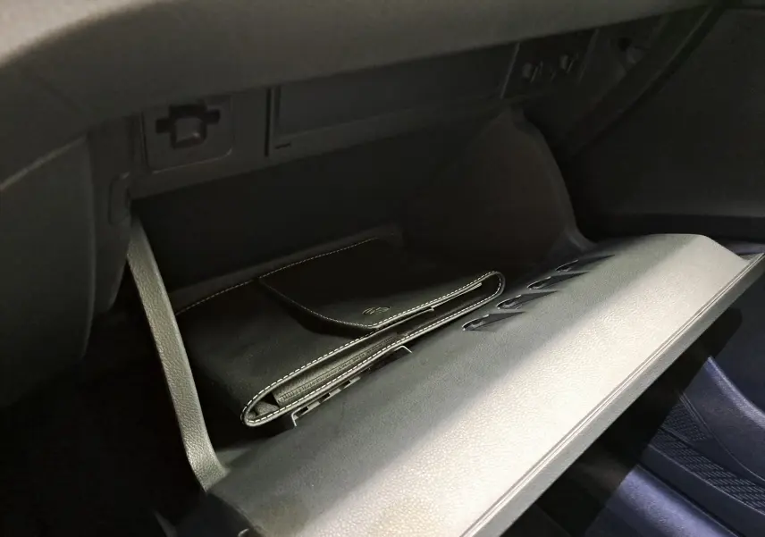 Gant de poche noir avec surpiqûres blanches dans la boîte à gants ouverte d’un Volkswagen Taigo 2025.