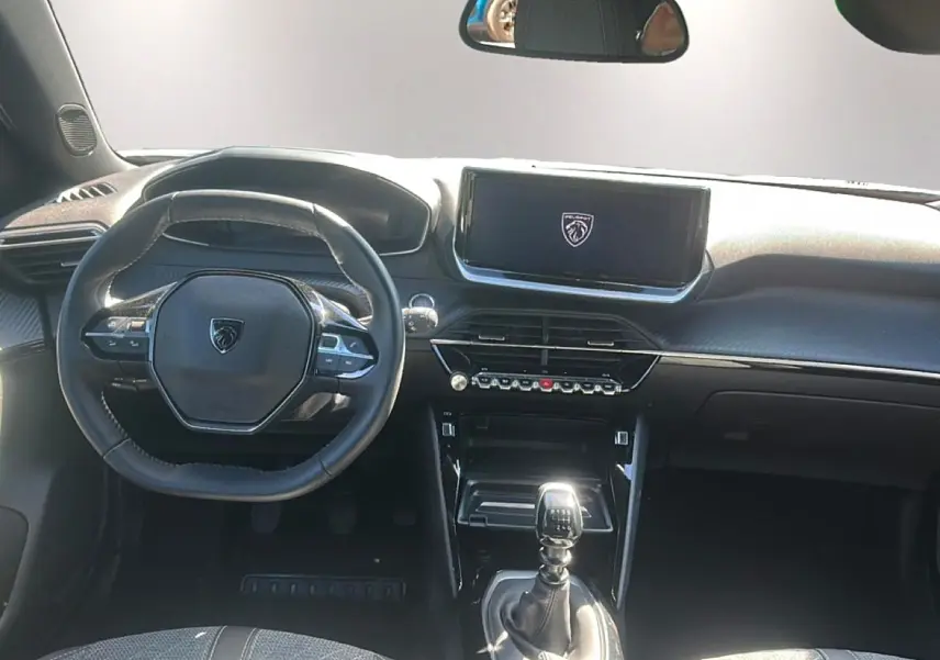 Vue intérieure avant du Peugeot 2008 1.2 100 allure 2025, volant multifonction et levier de vitesse manuel visibles.