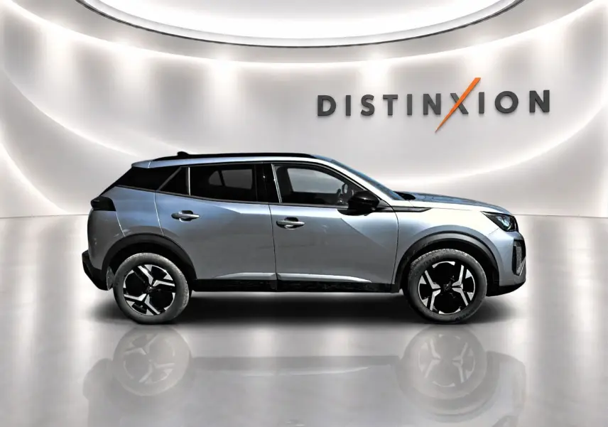 Profil droit du Peugeot 2008 1.2 100 Allure gris Artense avec jantes alu et toit noir dans un showroom lumineux.