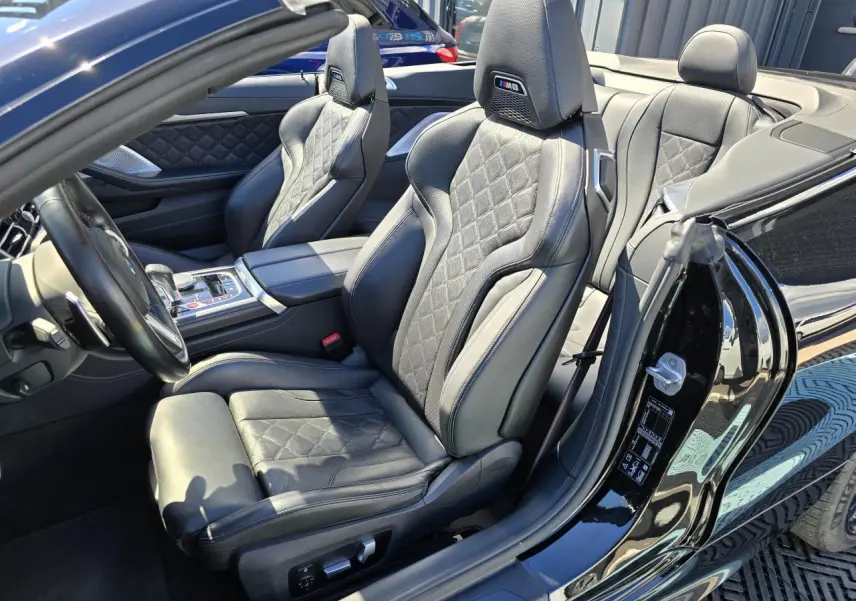 Intérieur cuir noir avec sièges M8 matelassés, vue côté conducteur d'un BMW Série 8 Cabriolet noir saphir métallisé.