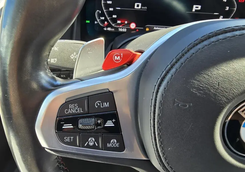 Gros plan sur le volant cuir noir de la BMW Série 8 Cabriolet M8 Competition avec commandes multifonctions et palette rouge M1.