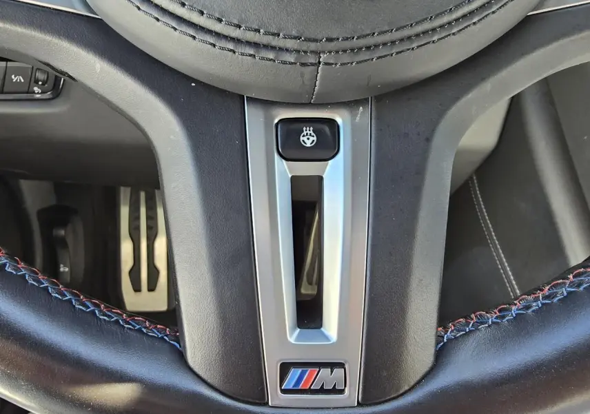 Gros plan sur le volant cuir noir avec surpiqûres tricolores et logo M de la BMW Série 8 Cabriolet M8 Competition.