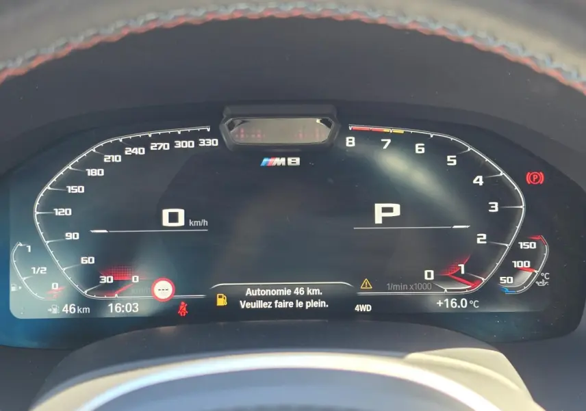 Tableau de bord numérique BMW M8 Competition affichant vitesse, régime moteur et autonomie restante de 46 km.