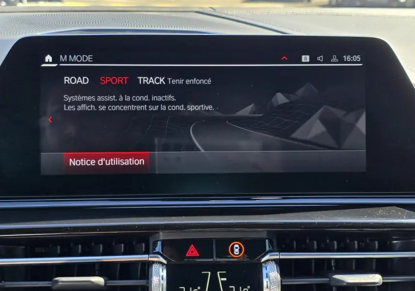 Écran central du tableau de bord BMW Série 8 Cabriolet M8 Competition affichant le mode de conduite Sport en intérieur noir.