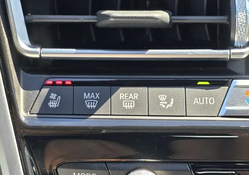 Gros plan sur les commandes de climatisation et sièges chauffants de la BMW Série 8 Cabriolet M8 Competition noir saphir métal.