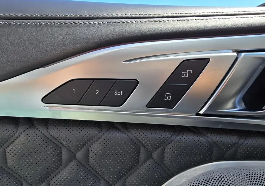 Détail des commandes de mémoire des sièges et verrouillage sur la portière côté gauche en cuir noir perforé d'une BMW Série 8 Cabriolet M8 Competition.