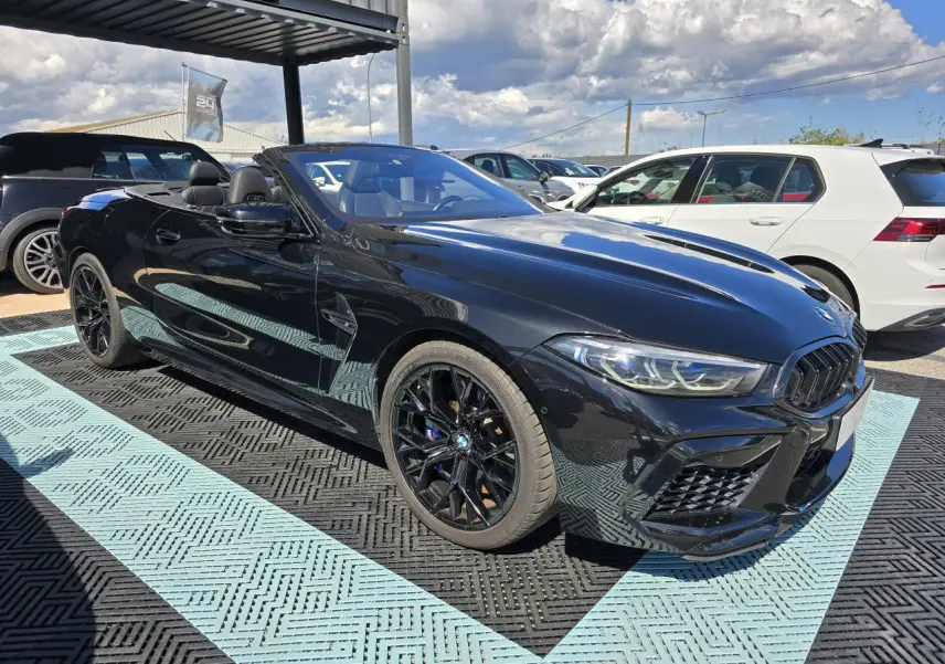 BMW Série 8 Cabriolet M8 Competition noir saphir métal, vue 3/4 avant droit avec jantes noires et capote ouverte.
