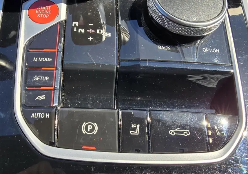 Gros plan sur la console centrale noire laquée du BMW Série 8 Cabriolet M8 Competition avec boutons de commande et molette.