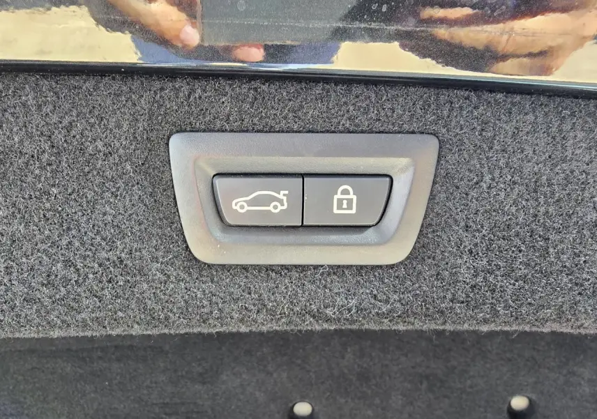 Gros plan sur les boutons d'ouverture et de verrouillage du coffre, intérieur noir en tissu du BMW Série 8 Cabriolet M8 Competition.