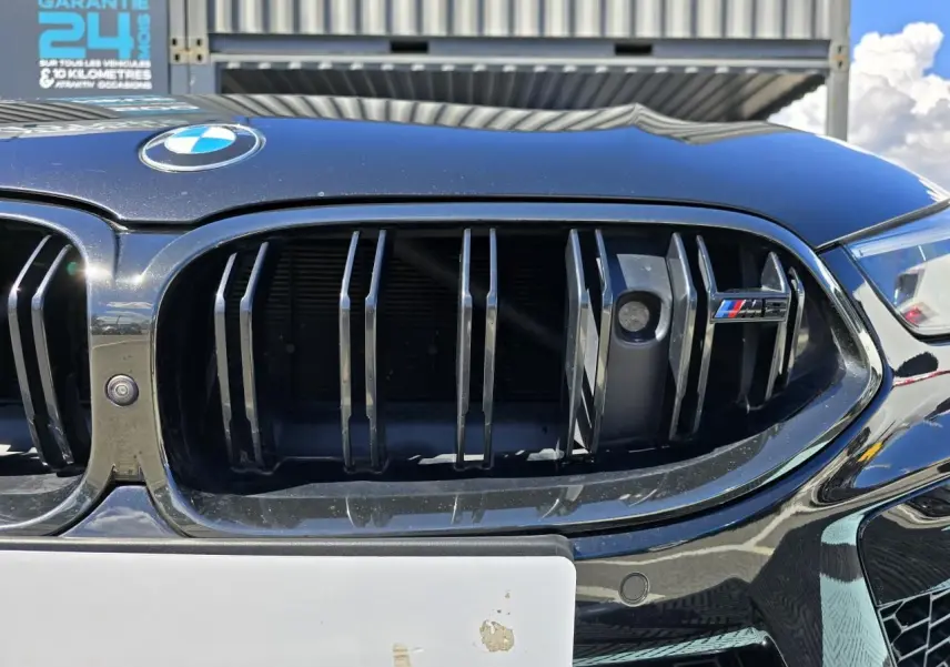 Gros plan sur la calandre noire brillante d'une BMW Série 8 Cabriolet M8 Competition 2021 avec logo M8 coloré.
