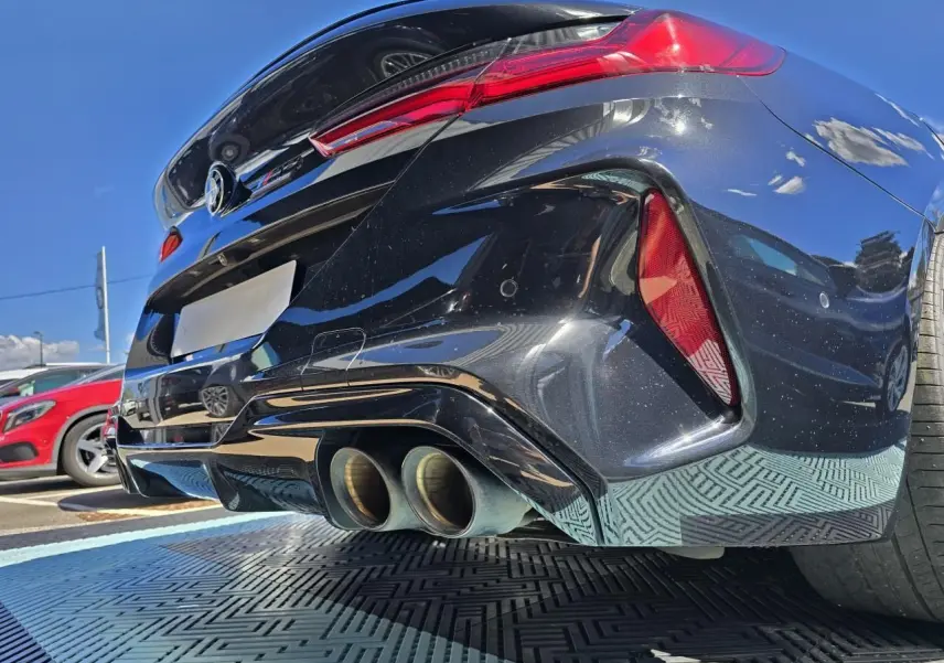 Vue en gros plan du diffuseur arrière et des doubles sorties d'échappement d'une BMW Série 8 Cabriolet M8 Competition noir saphir métal.