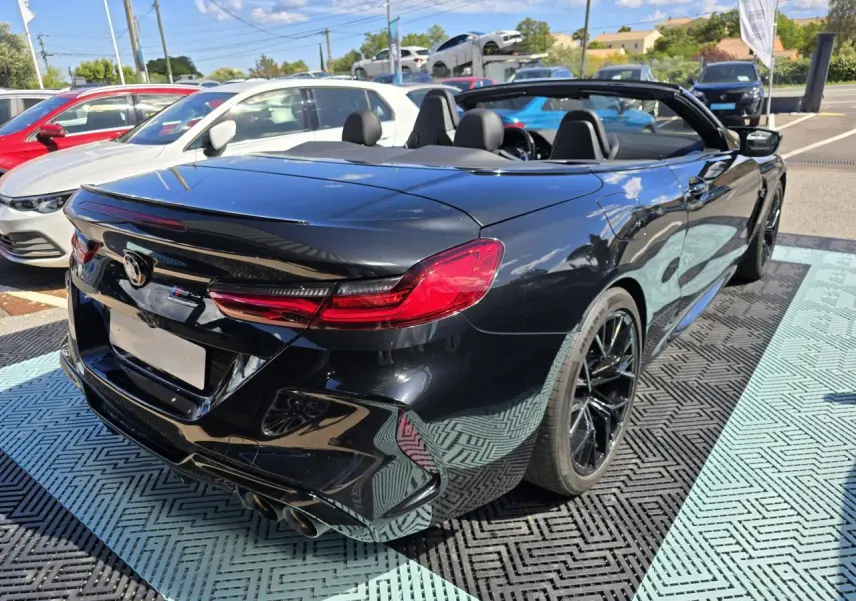 BMW Série 8 Cabriolet M8 Competition noir saphir, vue 3/4 arrière droit avec capote ouverte et jantes noires.