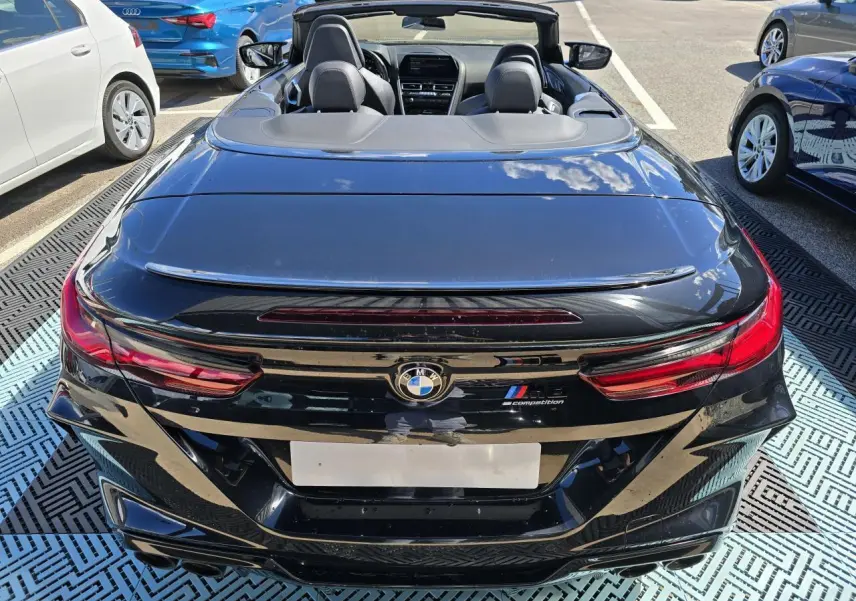 Vue arrière d'une BMW Série 8 Cabriolet M8 Competition noire avec capote ouverte et feux LED distinctifs.