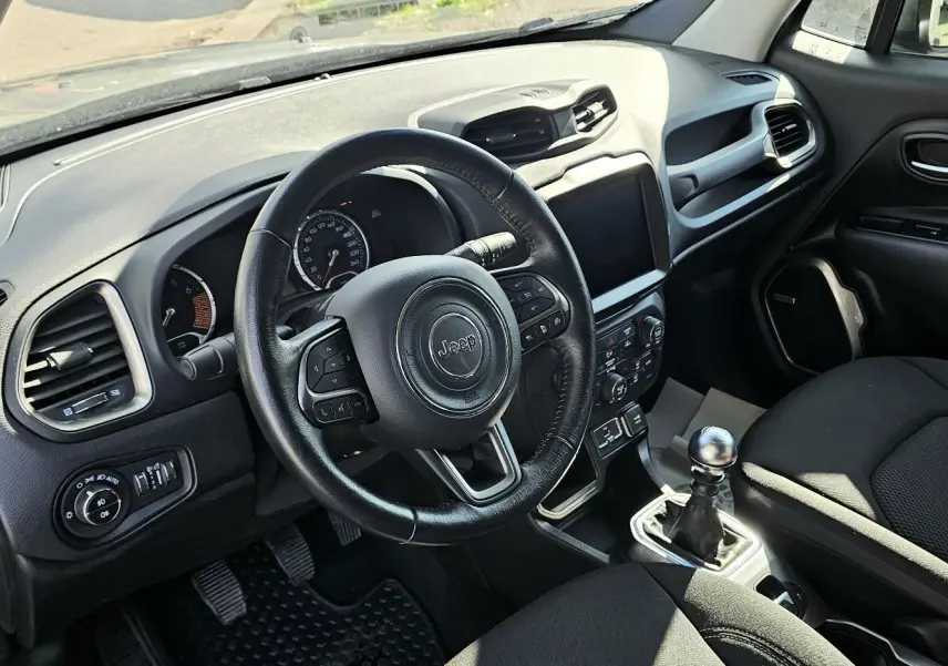 Intérieur du Jeep Renegade 2020 en tissu noir, vue côté conducteur sur le volant, tableau de bord et levier de vitesse manuel.