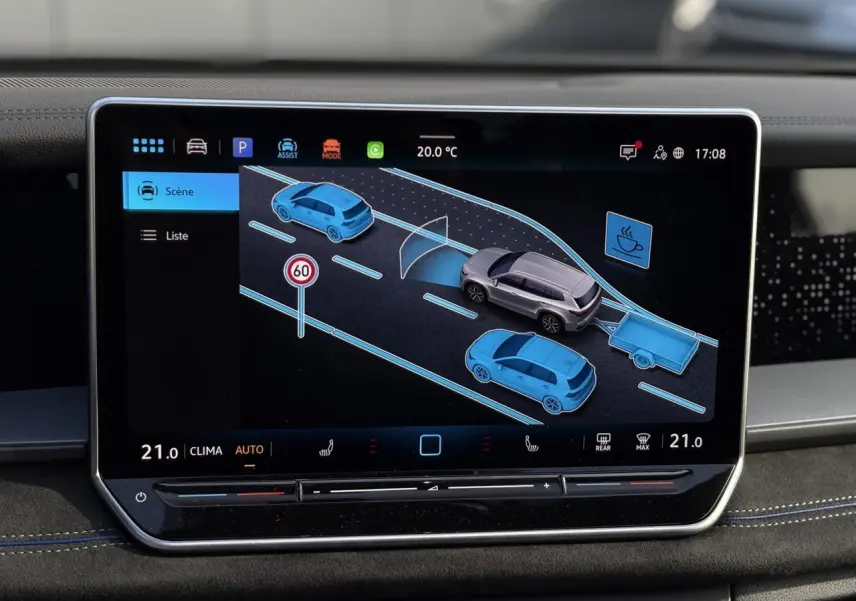 Écran tactile intérieur montrant l'assistance au stationnement avec vue 3D du Volkswagen Tayron gris dauphin et son attelage.