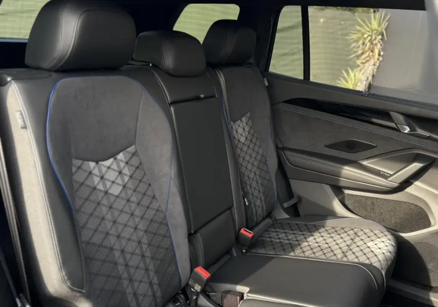 Vue intérieure côté droit des sièges arrière en tissu et cuir noir avec surpiqûres bleues du Volkswagen Tayron 2025.