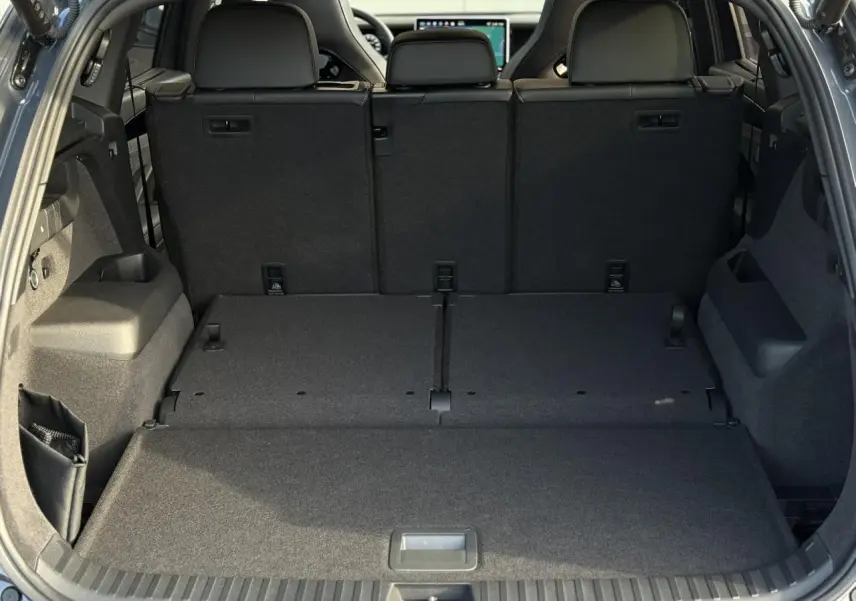 Vue du coffre arrière ouvert du Volkswagen Tayron 2.0 TDI gris dauphin avec banquette arrière relevée et espace de chargement plat.