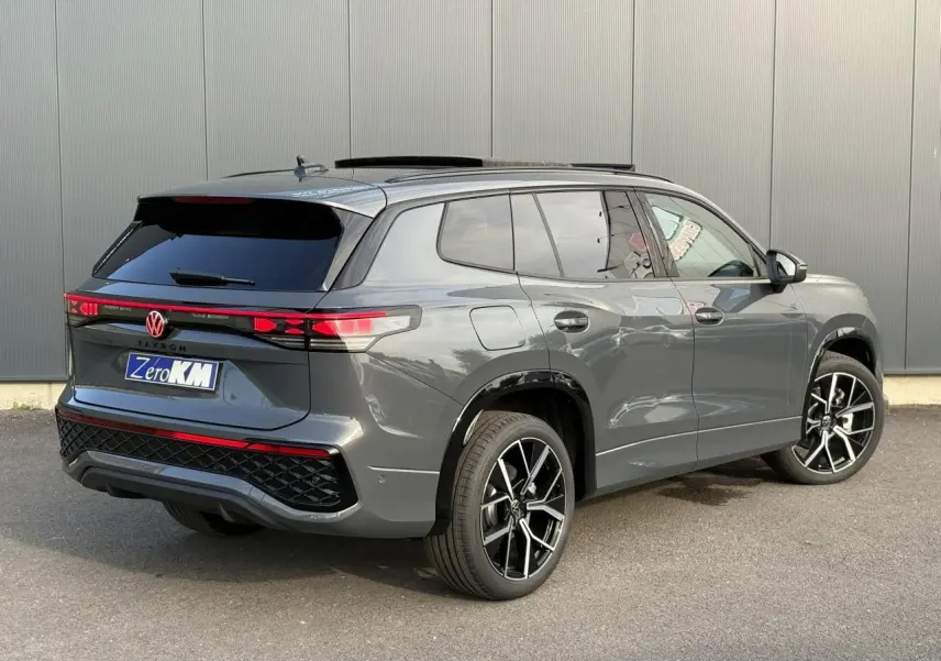 Vue 3/4 arrière droite du Volkswagen Tayron gris dauphin avec jantes alliage noires et vitres surteintées.