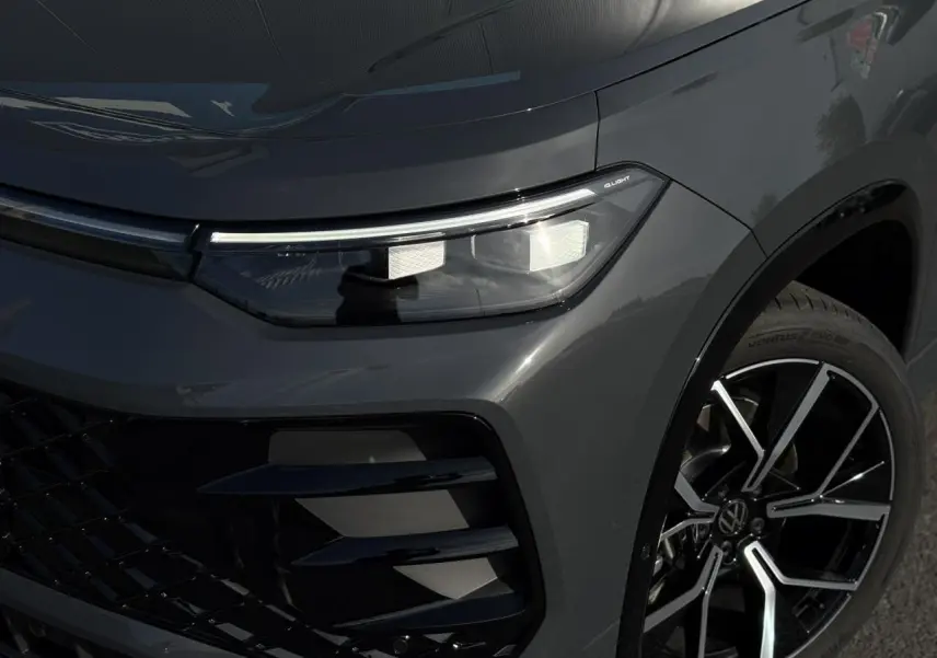 Gros plan sur l'avant droit gris dauphin du Volkswagen Tayron 2025, avec projecteur IQ.Light Matrix LED et jante alliage 20 pouces.