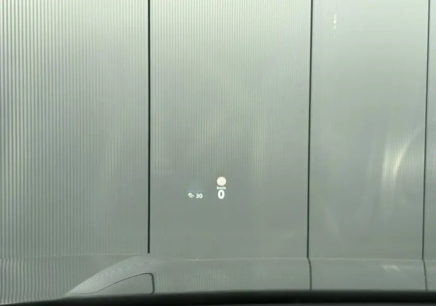 Vue depuis l'intérieur du Volkswagen Tayron gris dauphin, affichage tête haute projetant la vitesse et limite sur pare-brise.