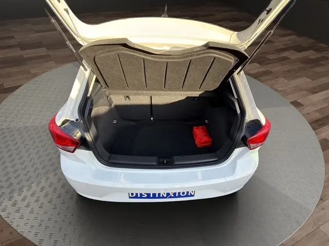 Vue arrière d'une SEAT Ibiza blanche 2023 avec coffre ouvert et un triangle de signalisation rouge visible à l'intérieur.