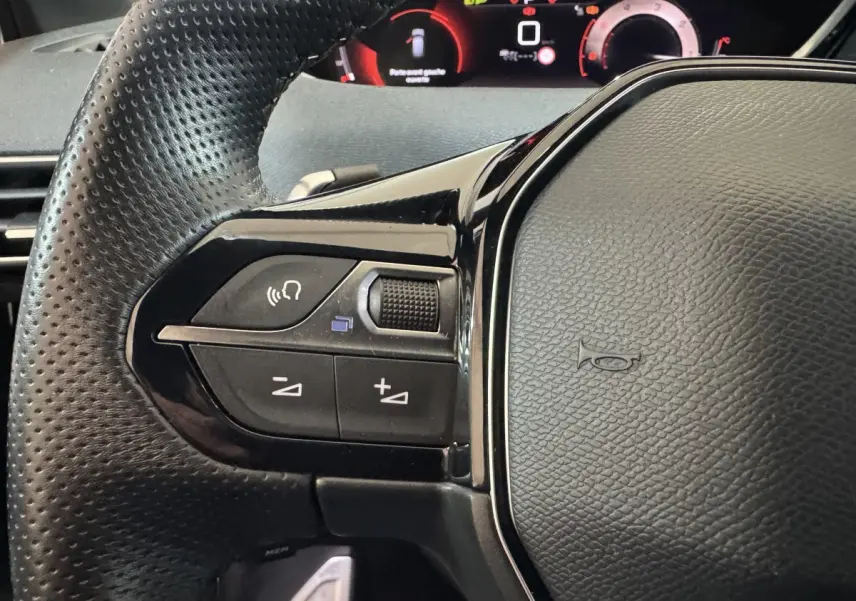 Gros plan sur le volant cuir perforé côté gauche du Peugeot 3008 GT 2021 avec commandes vocales et tableau de bord numérique.