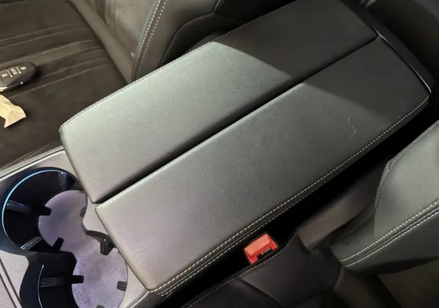 Vue rapprochée de l'accoudoir central noir et des sièges en cuir gris foncé à coutures blanches du Peugeot 3008 GT 2021.