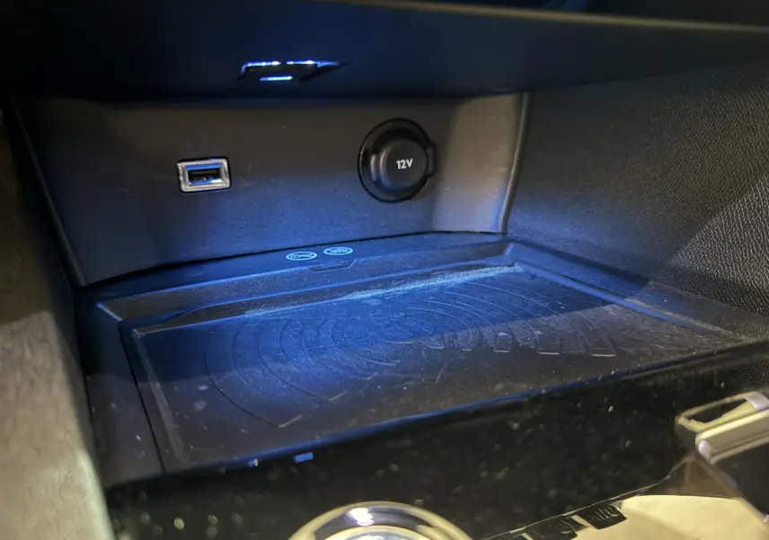 Vue rapprochée de la console centrale du Peugeot 3008 gris clair, avec prise USB, prise 12V et zone de recharge sans fil.