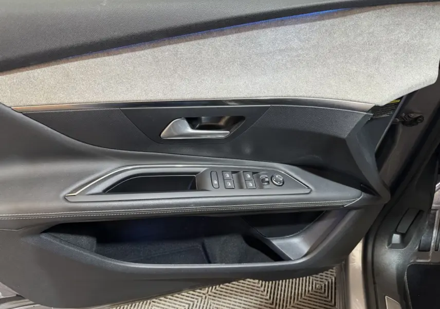 Intérieur côté gauche de la porte avant d'un Peugeot 3008 gris clair, avec commandes des vitres et poignée métallique.