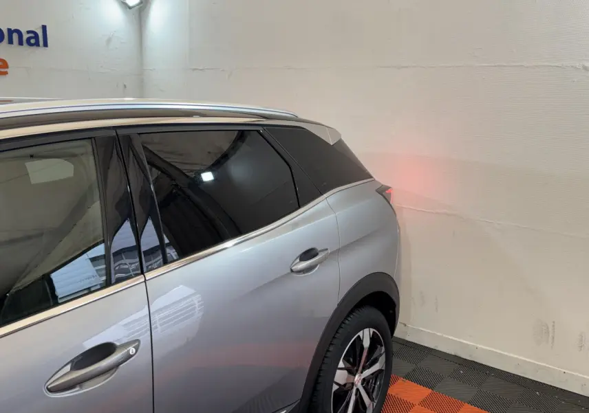 Vue côté gauche arrière d'un Peugeot 3008 gris clair avec vitres teintées et jantes alliage noires et argentées.