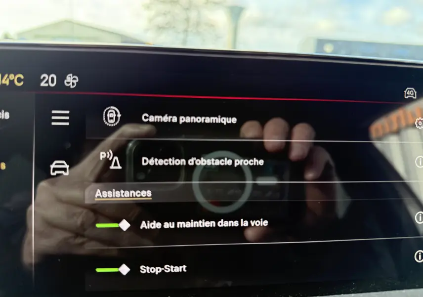 Écran tactile intérieur de la DS3 hybride 2025 affichant les assistances à la conduite avec reflet de mains.