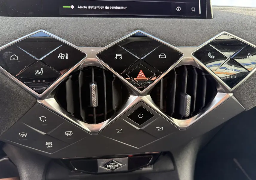 Détail du tableau de bord du DS3 2025 hybride, montrant les commandes climatisation et ventilation avec finition noire brillante.
