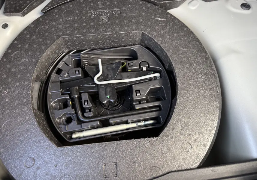 Gros plan sur le rangement d'outils dans le coffre d'une DS3 Hybride 145 gris Artense avec toit noir, année 2025.