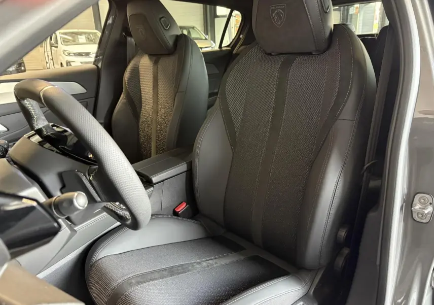Vue intérieure côté conducteur de la Peugeot 308 gris selenium, siège sport cuir/tissu avec logo Peugeot brodé sur l'appuie-tête.