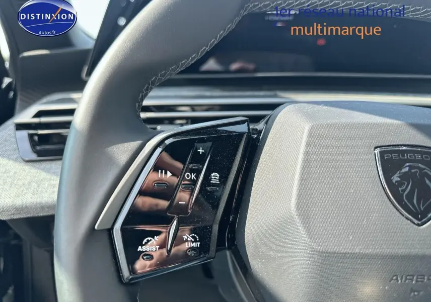 Gros plan sur le volant cuir noir du Peugeot 3008 2025, avec commandes multifonctions et logo lion central gris.