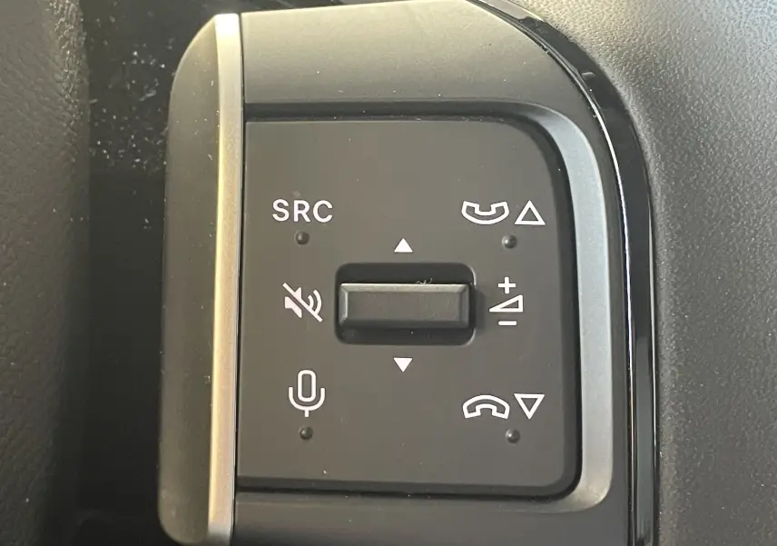 Gros plan sur les commandes au volant noir de la Citroën E-C3 113 MAX, avec boutons de volume et téléphone intégrés.