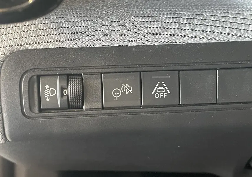 Gros plan sur les commandes du tableau de bord de la Citroën E-C3 113 MAX noire, avec réglage des phares et aides à la conduite.