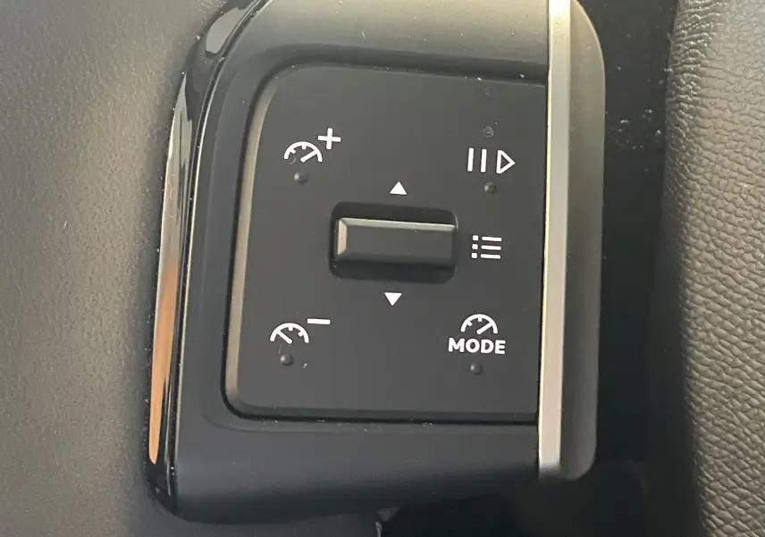 Gros plan sur les commandes de régulateur de vitesse au volant du Citroën E-C3 113 MAX noir, intérieur 2025.