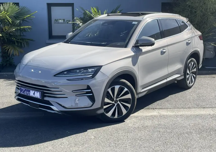 Vue 3/4 avant droite du SUV BYD SEAL U 2025 en beige métallisé Boundless Cloud avec jantes bicolores et barres de toit.