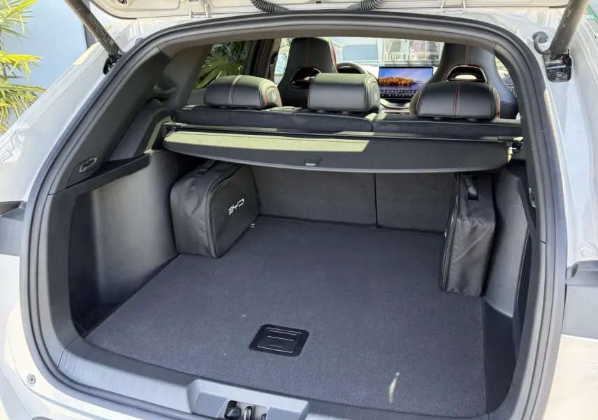 Coffre ouvert du BYD SEAL U beige Boundless Cloud, montrant un espace de chargement avec cache-bagages et sacs latéraux.