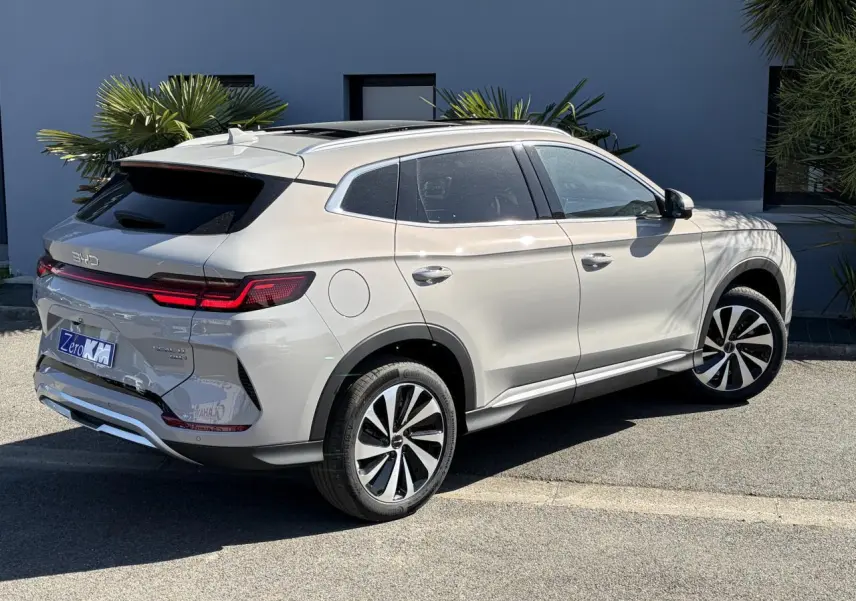 Vue 3/4 arrière droite du BYD SEAL U beige Boundless Cloud avec toit panoramique et feux arrière LED allumés.