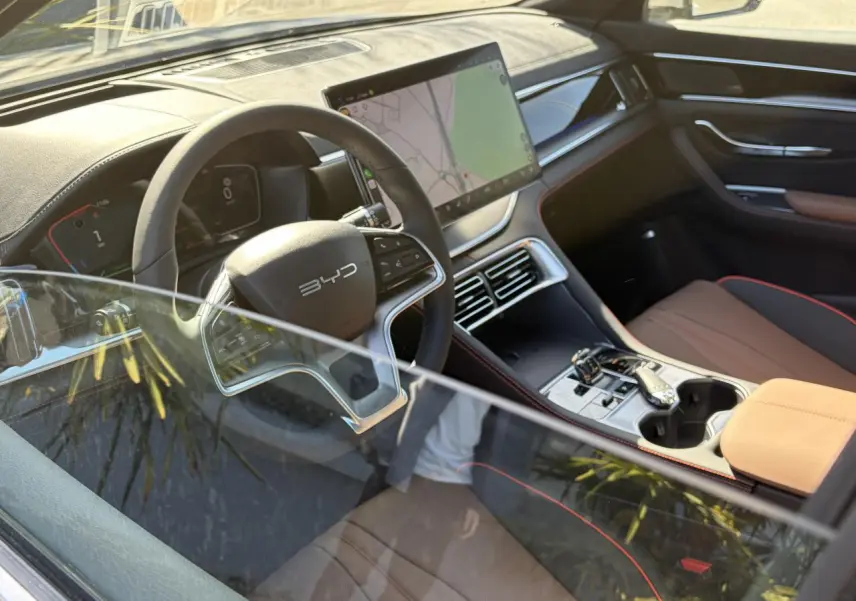 Vue intérieure côté conducteur du BYD SEAL U 2025 avec habitacle noir et brun, écran tactile central et volant multifonction.