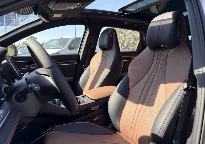 Intérieur du BYD SEAL U 2025 vu côté conducteur, sièges noir et brun avec surpiqûres rouges et toit panoramique.