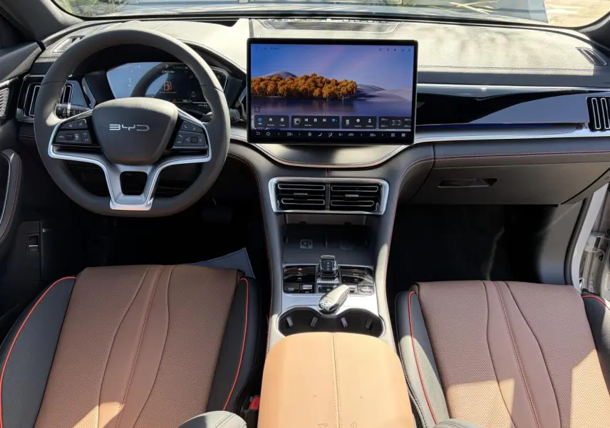 Vue intérieure avant du BYD SEAL U 2025 avec tableau de bord noir et brun, écran tactile 15,6 pouces et volant multifonction.